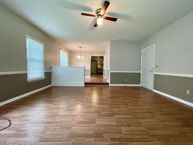  - unfurnished living room with wood finished floors, ceiling fan, and a chandelier
