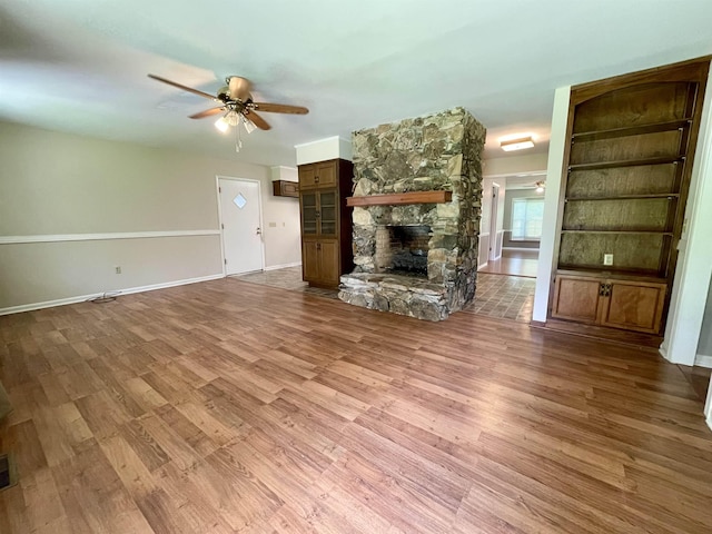  - unfurnished living room featuring wood finished floors, ceiling fan, and a fireplace