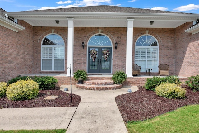  - property entrance with covered porch, brick siding, and french doors