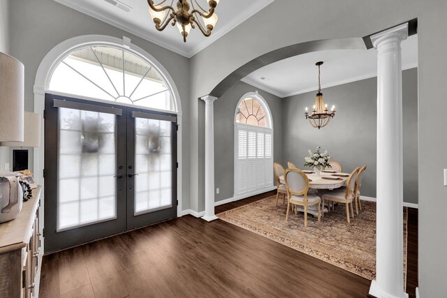  - dining area featuring a chandelier, dark wood-style floors, french doors, decorative columns, and crown molding