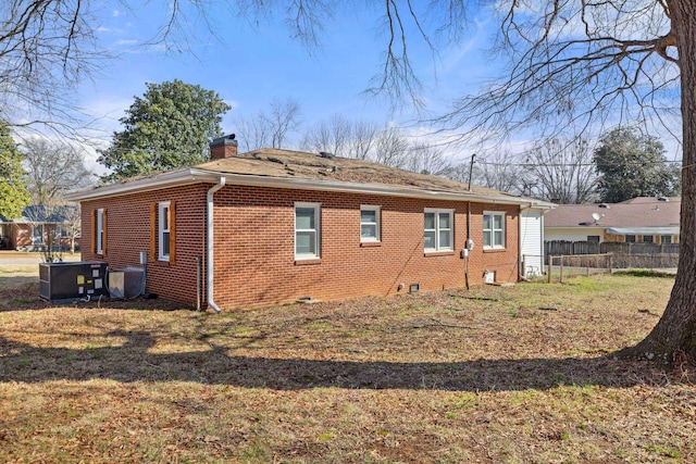 view of property exterior with crawl space, a chimney, fence, and brick siding