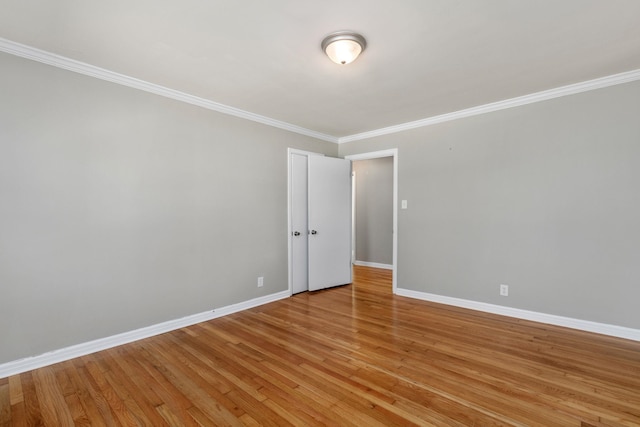 spare room with crown molding, light wood finished floors, and baseboards