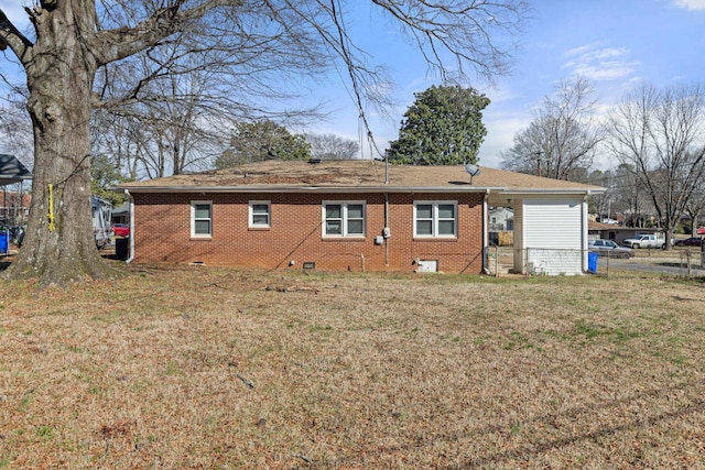 rear view of house with a yard, brick siding, and crawl space