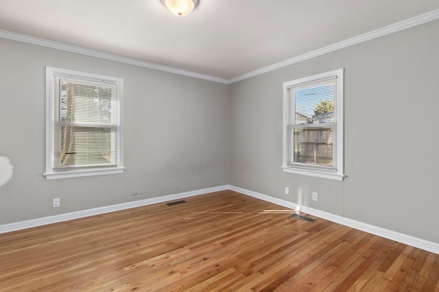 spare room featuring light wood-type flooring, baseboards, visible vents, and ornamental molding