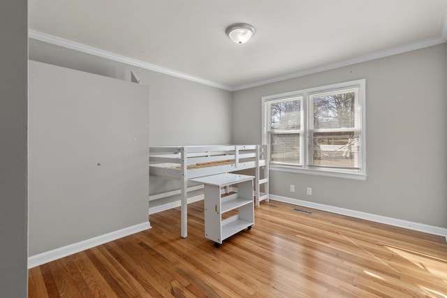 bedroom with crown molding, light wood finished floors, visible vents, and baseboards