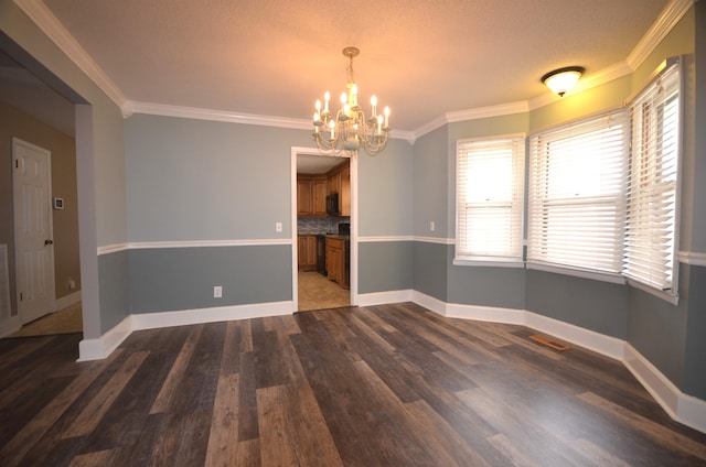 unfurnished dining area featuring crown molding, dark hardwood / wood-style floors, and a chandelier