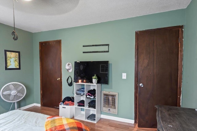 bedroom featuring hardwood / wood-style floors, a textured ceiling, heating unit, and ceiling fan