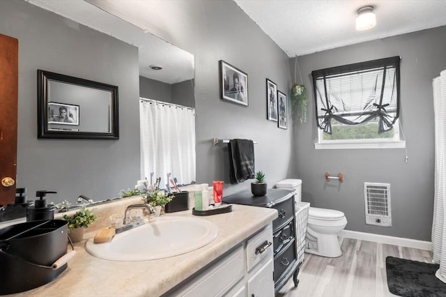 bathroom with vanity, hardwood / wood-style flooring, toilet, a textured ceiling, and heating unit