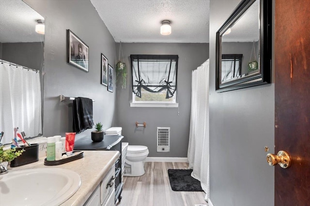 bathroom with vanity, a textured ceiling, heating unit, wood-type flooring, and toilet