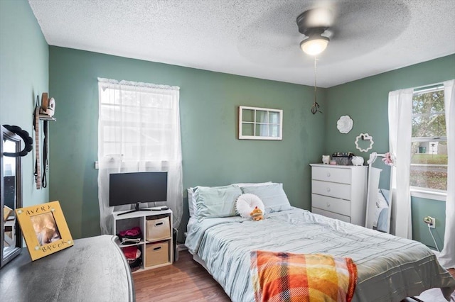 bedroom with ceiling fan, light wood-type flooring, and a textured ceiling