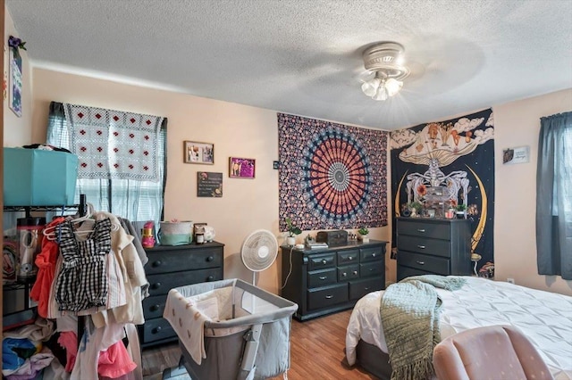 bedroom featuring ceiling fan, light hardwood / wood-style flooring, and a textured ceiling