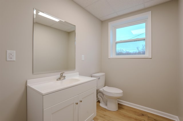 bathroom with hardwood / wood-style floors, vanity, a paneled ceiling, and toilet