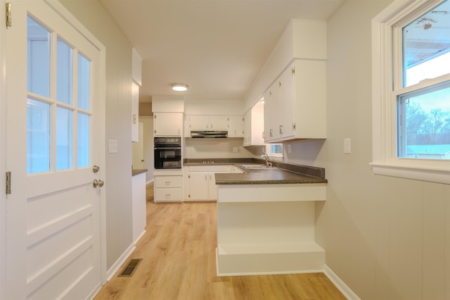 kitchen featuring white cabinetry, sink, oven, and light hardwood / wood-style flooring