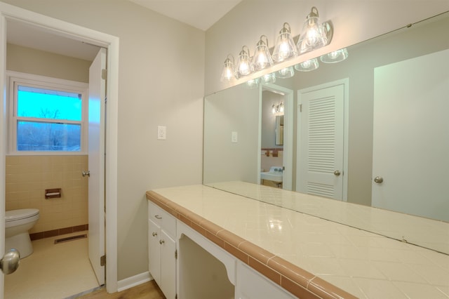 bathroom with vanity, tile walls, and toilet