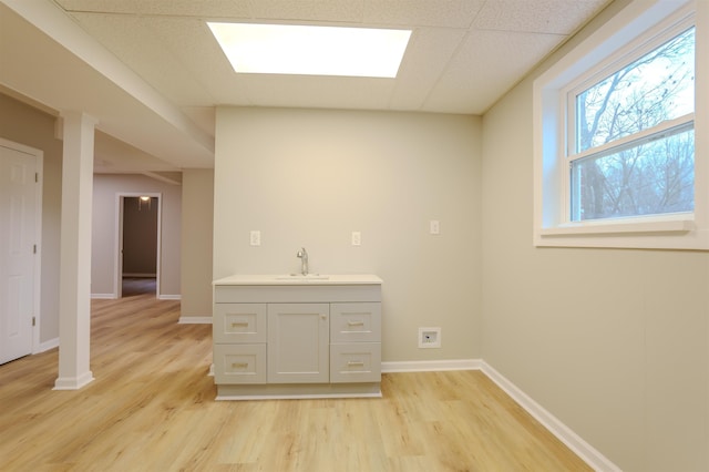 interior space featuring sink, a paneled ceiling, and light hardwood / wood-style flooring