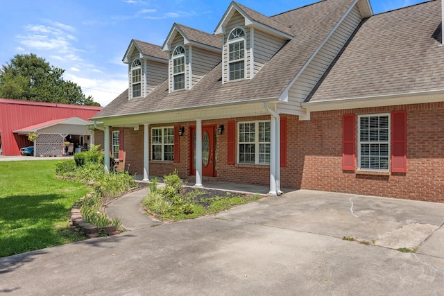 cape cod-style house featuring a carport, covered porch, and a front lawn