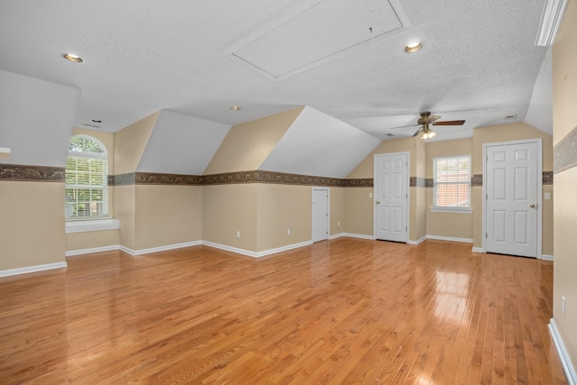 bonus room featuring ceiling fan, light hardwood / wood-style floors, lofted ceiling, and a textured ceiling