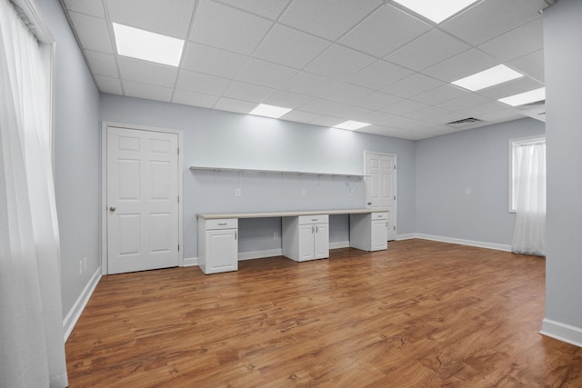 unfurnished office with light wood-type flooring, built in desk, and a wealth of natural light