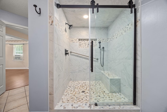 bathroom with tile patterned flooring, a shower with shower door, and a textured ceiling