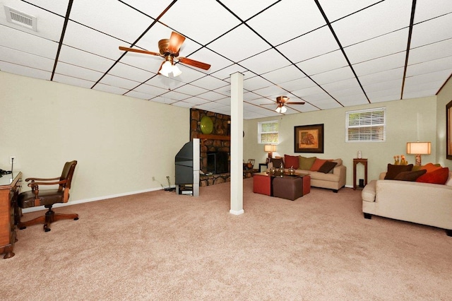 living room featuring a stone fireplace, ceiling fan, and light colored carpet