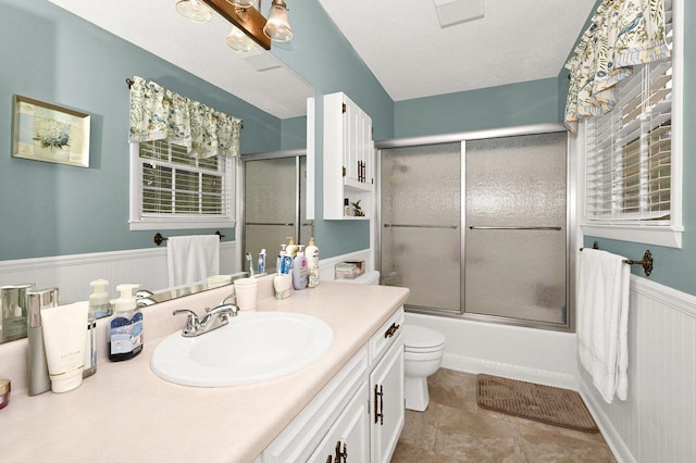 full bathroom with vanity, shower / bath combination with glass door, tile patterned flooring, toilet, and a textured ceiling