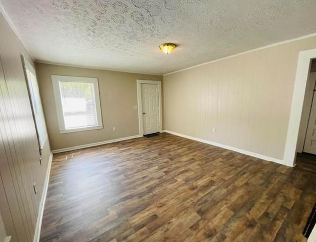 spare room with a textured ceiling, wooden walls, and dark hardwood / wood-style floors