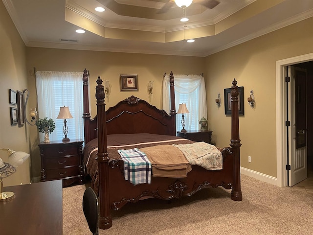 bedroom with ornamental molding, light carpet, ceiling fan, and a tray ceiling