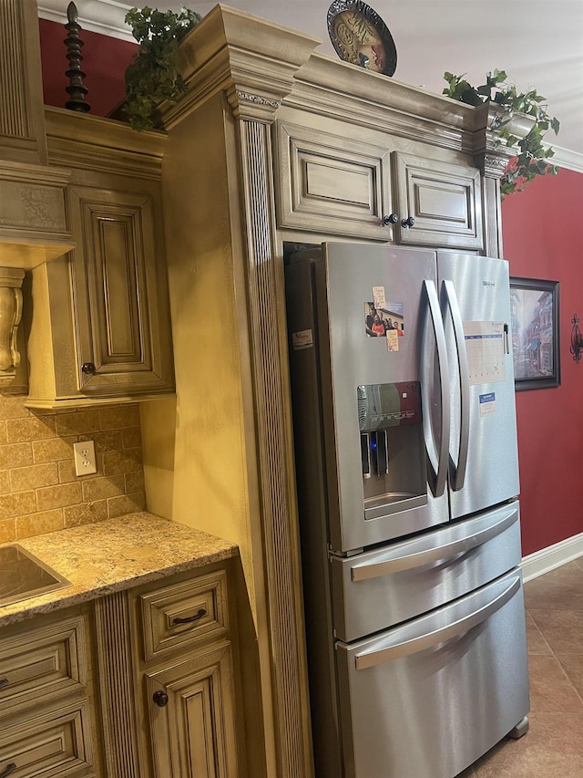 kitchen with light tile patterned flooring, light stone countertops, stainless steel fridge, and backsplash