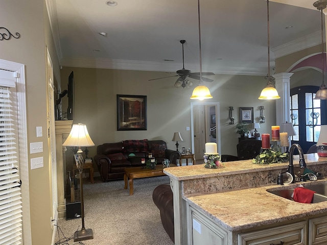 kitchen with pendant lighting, sink, ornamental molding, light colored carpet, and ceiling fan