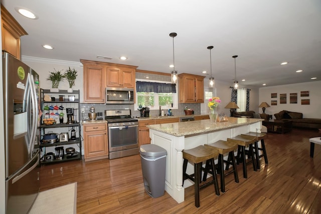  - kitchen with appliances with stainless steel finishes, a center island, open floor plan, backsplash, and ornamental molding