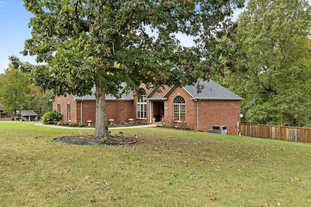 view of front facade featuring a front yard, central AC unit, fence, and brick siding