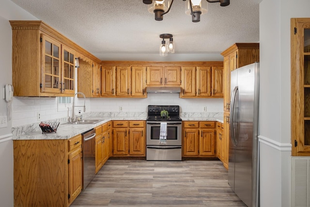 kitchen with stainless steel appliances, light countertops, visible vents, a sink, and under cabinet range hood