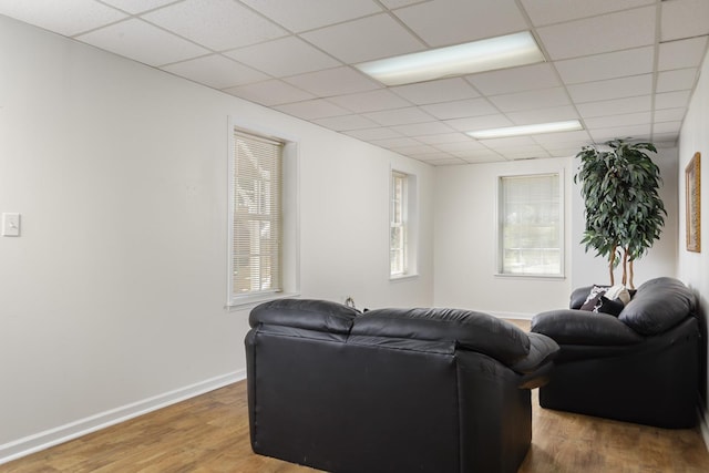 living room with baseboards, a drop ceiling, and wood finished floors