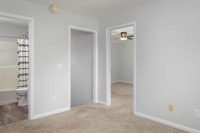 unfurnished bedroom featuring carpet floors, connected bathroom, baseboards, and a textured ceiling