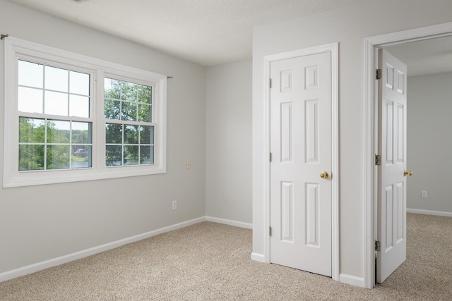 unfurnished bedroom featuring carpet, baseboards, and a textured ceiling