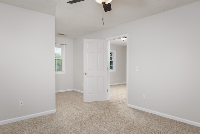 empty room with carpet floors, baseboards, visible vents, and a textured ceiling