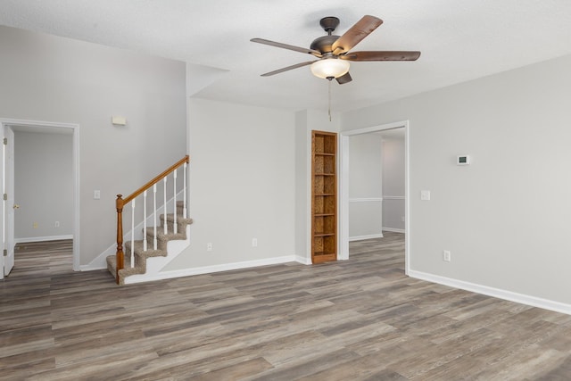 spare room with stairs, baseboards, and wood finished floors