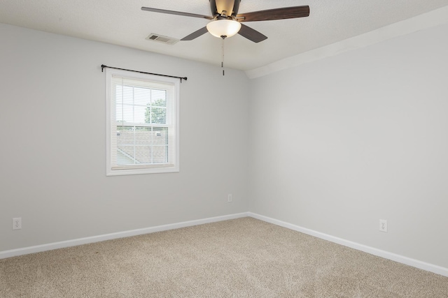 carpeted spare room featuring visible vents, ceiling fan, a textured ceiling, and baseboards