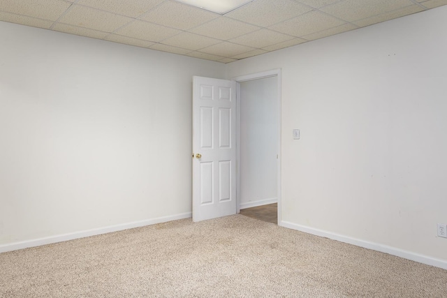 carpeted empty room with a paneled ceiling and baseboards