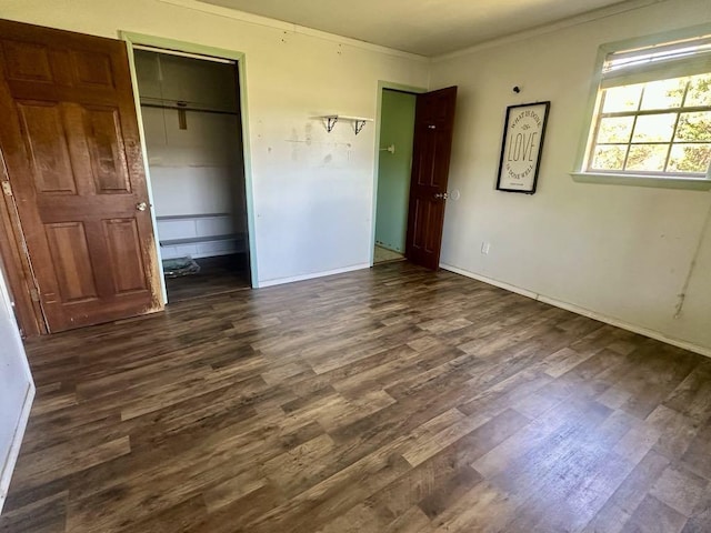  - unfurnished bedroom featuring dark wood-type flooring, crown molding, baseboards, and a closet