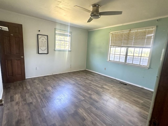  - spare room featuring a ceiling fan, dark wood finished floors, ornamental molding, and baseboards