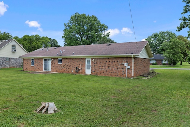  - back of property with a yard, brick siding, a patio, and roof with shingles