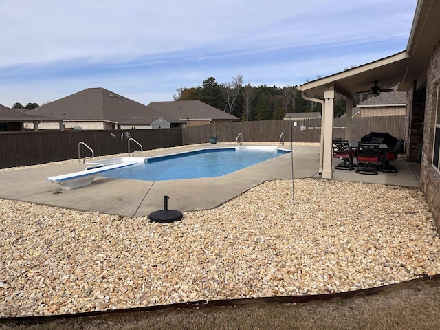 view of swimming pool featuring a patio, ceiling fan, and a diving board