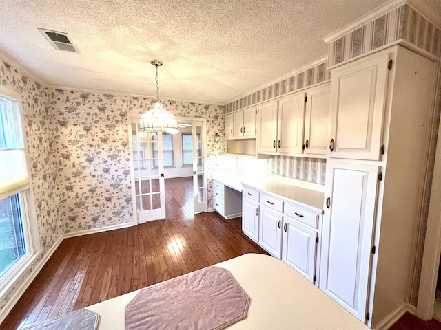 kitchen with a textured ceiling, decorative light fixtures, an inviting chandelier, dark hardwood / wood-style floors, and white cabinetry