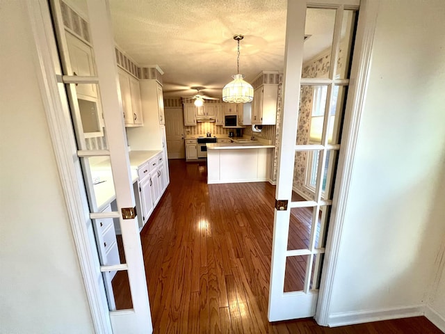 kitchen with range, dark hardwood / wood-style floors, a textured ceiling, decorative light fixtures, and white cabinetry