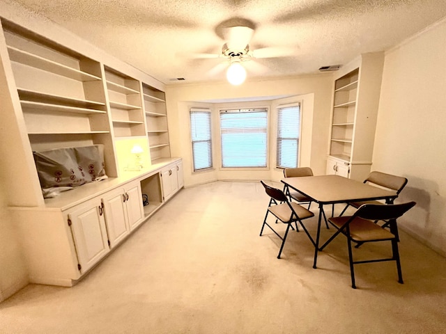 dining space featuring light carpet, a textured ceiling, and ceiling fan