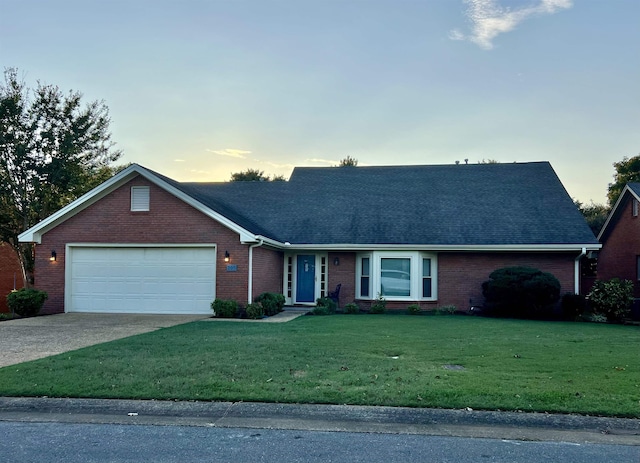 ranch-style house featuring a garage and a yard