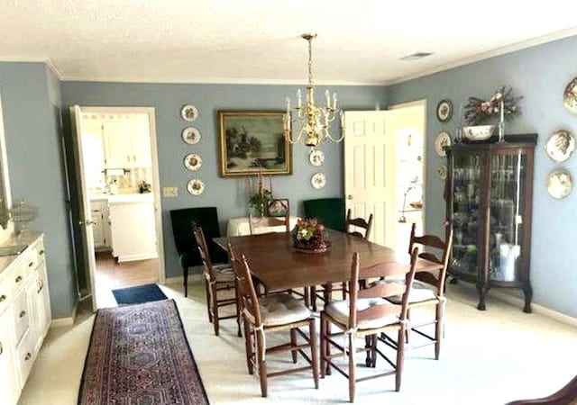 dining space featuring light carpet, a textured ceiling, crown molding, and a notable chandelier