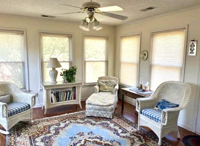 living area with wood-type flooring, a textured ceiling, ceiling fan, and crown molding