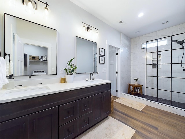 bathroom with hardwood / wood-style floors, vanity, and tiled shower